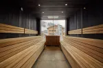 Innenansicht einer Holzsauna mit Bänken und großen Fenstern
