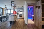 Modern kitchen with wooden floor, red refrigerator, and access to a bathroom.