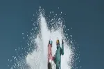 Two people skiing through water splash