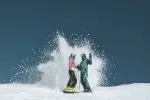 Two snowboarders creating a splash on the snow