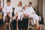 Family in bathrobes sitting on stools by a sofa