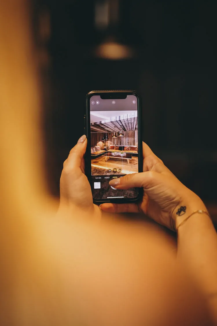 Hand einer Person hält ein Smartphone mit einem Bild von einem Innenraum.