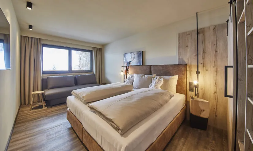 Modernes Schlafzimmer mit zwei Betten, einem Sofa und großem Fenster