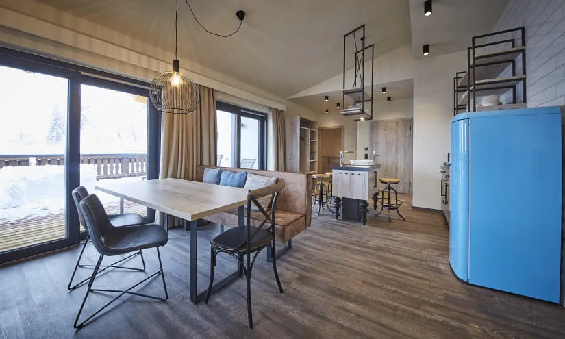 Moderne Küche und Essbereich mit einem blauen Kühlschrank und großen Fenstern