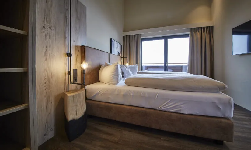 Gemütliches Hotelzimmer mit einem Doppelbett, Holzdekoration und einem Fensterblick