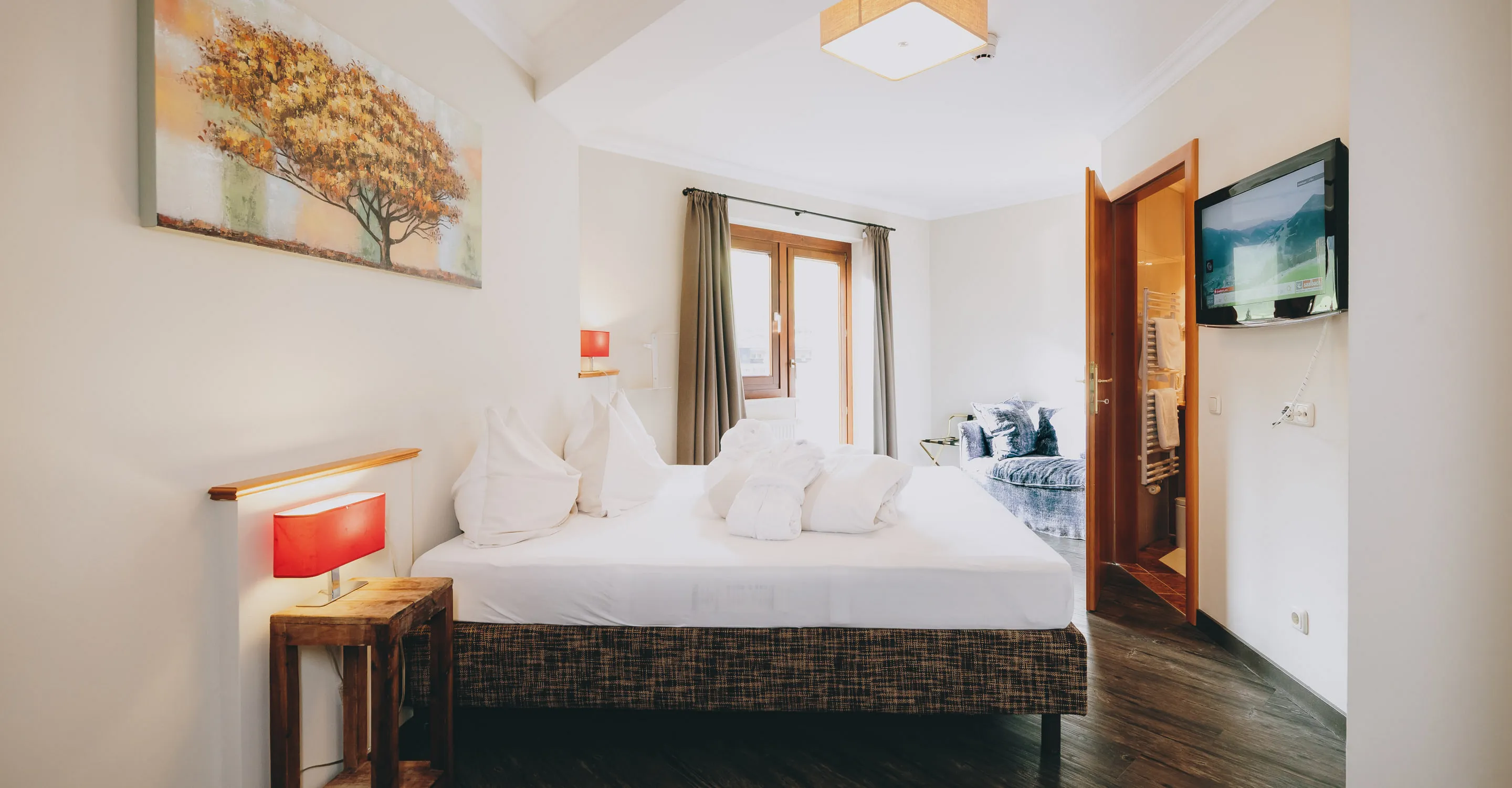Bedroom with bed, artwork, TV, and window.