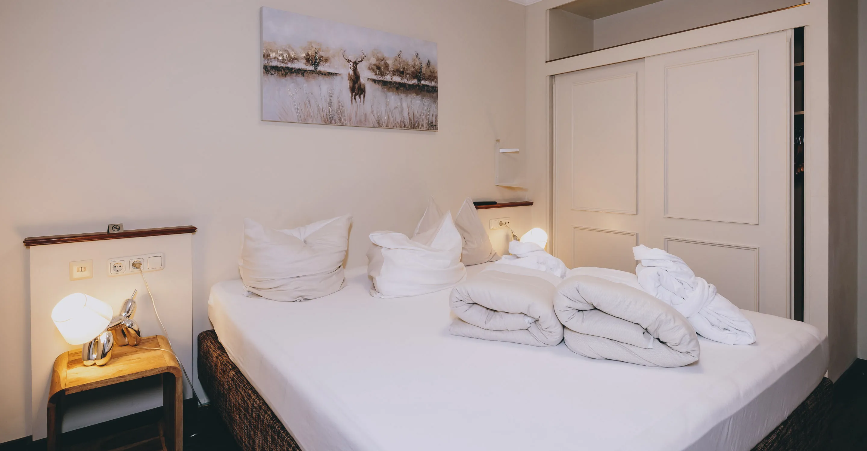 Room with a double bed, decorated pillows, and light-colored walls