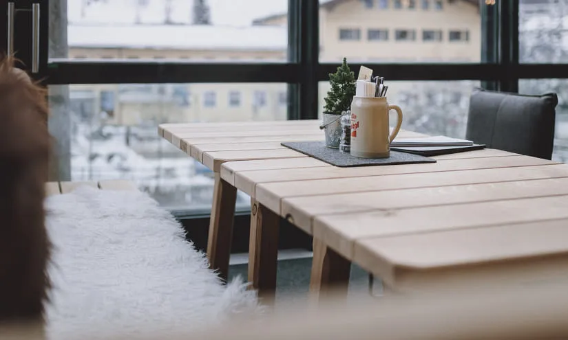 Holztisch auf Terrasse mit Aussicht, Tasse und Pflanzen.