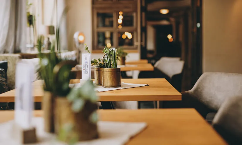 Helle Restaurantansicht mit Tischen und Pflanzen auf den Tischen.