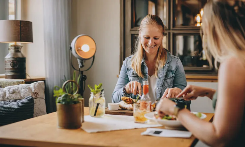 Zwei Frauen genießen eine Mahlzeit in einem gemütlichen Raum.
