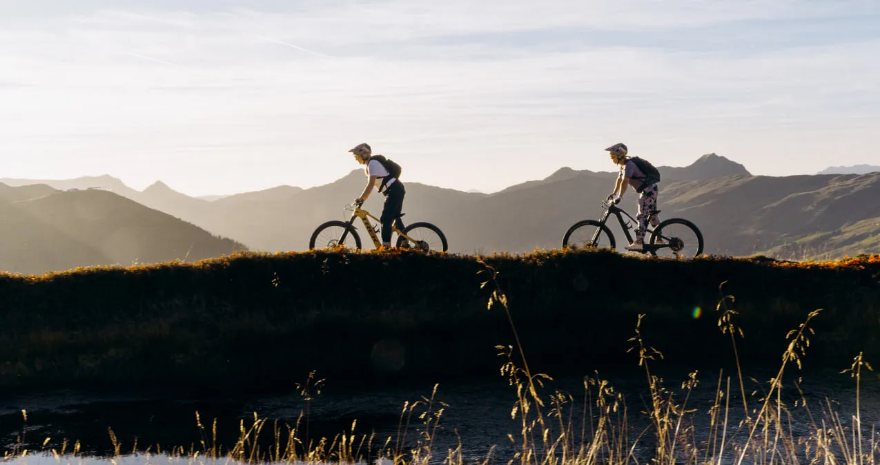 E-Mountainbiker fahren in Saalbach Hinterglemm bei Sonnenuntergang