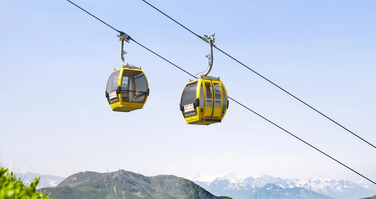 Gelbe Gondeln schwanken über einer Berglandschaft in Saalbach Hinterglemm
