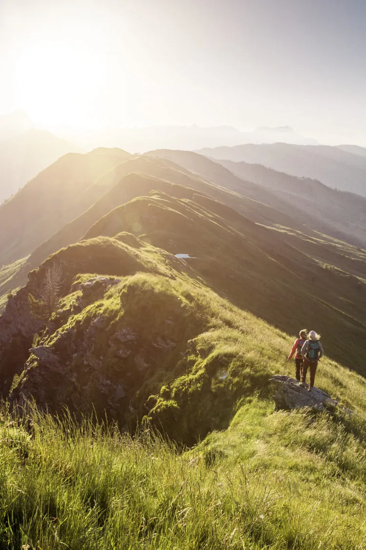Wanderer auf einem Bergpfad in Saalbach Hinterglemm bei Sonnenaufgang
