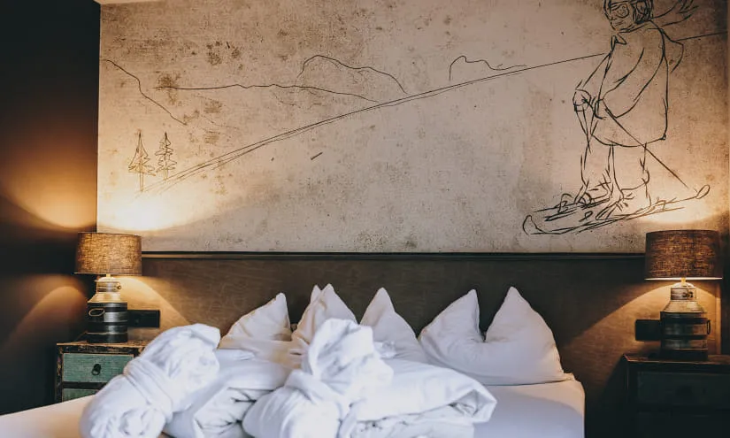 Gemütliches Hotelzimmer mit Bettwäsche und Wandkunst eines Snowboarders