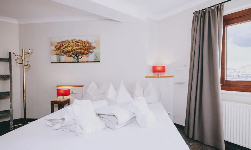 Modernes Hotelzimmer mit Bett, Handtüchern, Fenster und Malerei.