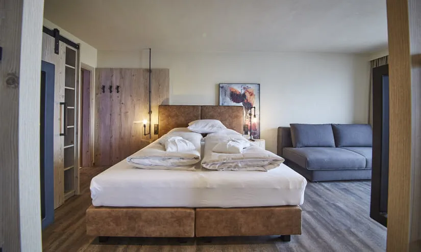 Modernes Hotelzimmer mit Bett, Couch und holzverziertem Dekor