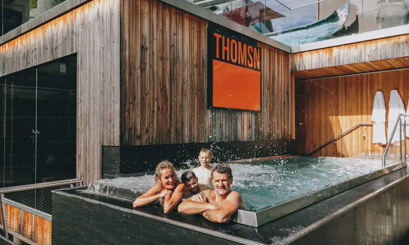 Personen im Außenbereich eines Spas mit Holzverkleidung und Pool