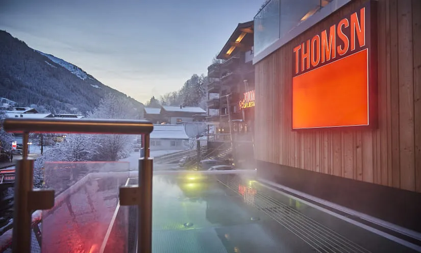 Bergsicht mit einem Pool und THOMSN-Schild bei Sonnenuntergang