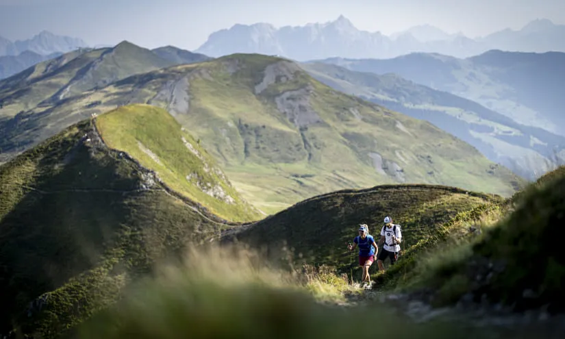 Wanderer auf einem Pfad in Saalbach Hinterglemm mit Berglandschaft im Hintergrund