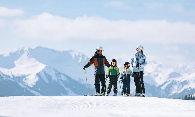 Familie in Skiausrüstung vor schneebedeckten Bergen