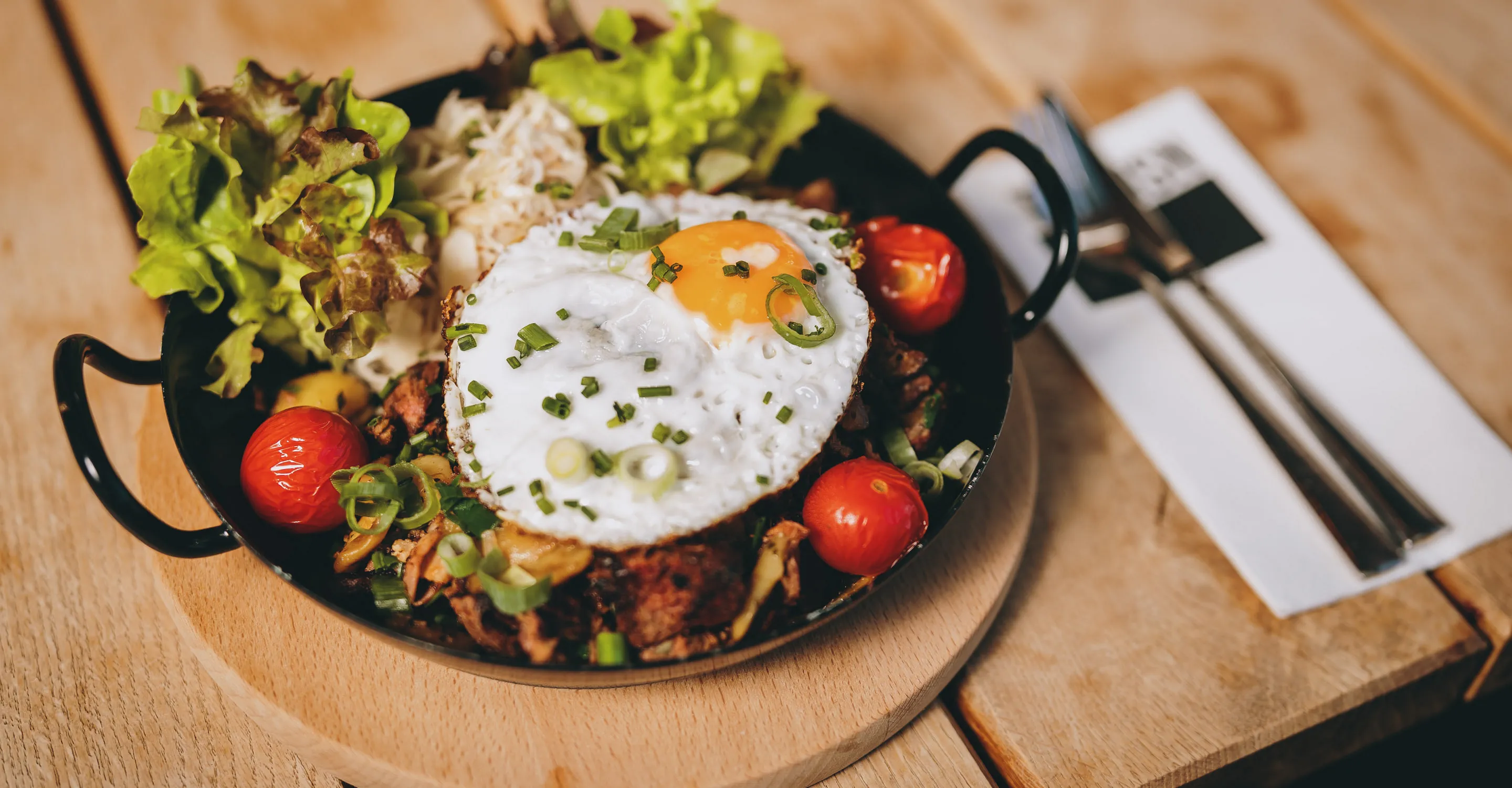 Teller mit Salat, Gemüse, beehaltenem Ei und Tomaten