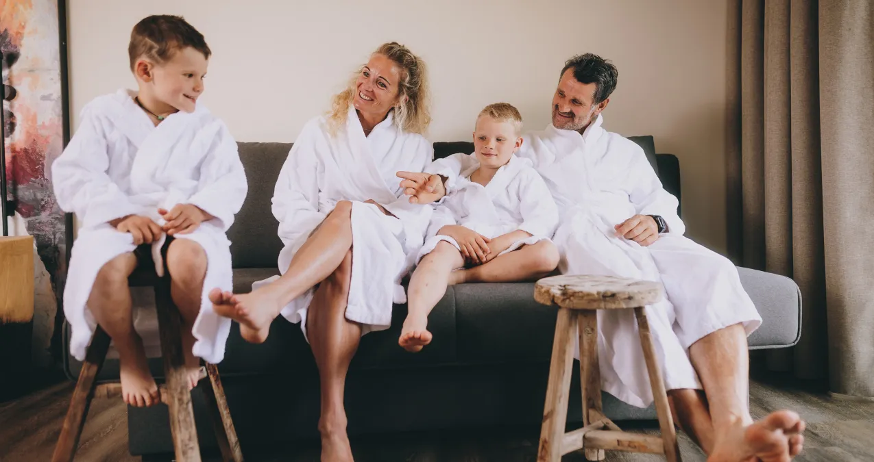Family in bathrobes sitting on a couch, cheerful atmosphere, children laughing.