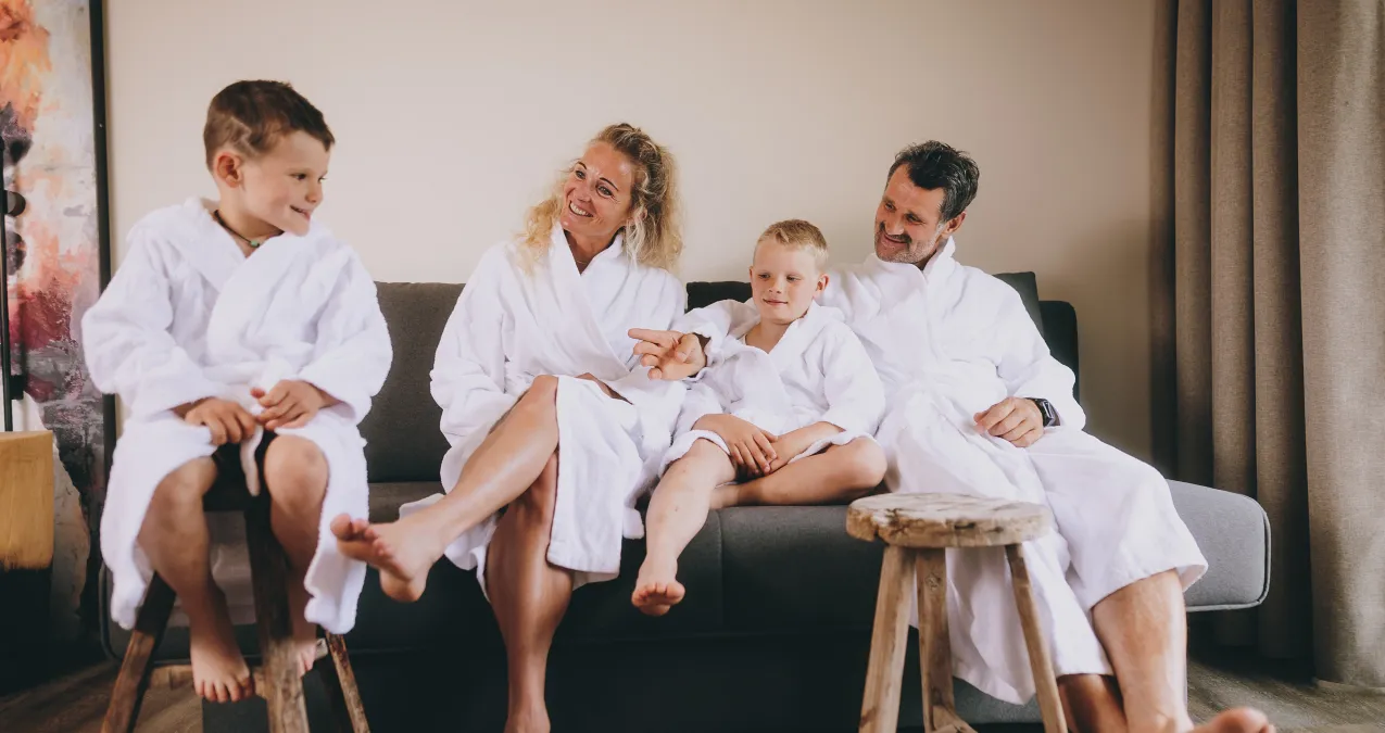 Familie in weißen Bademänteln sitzt auf einer Couch