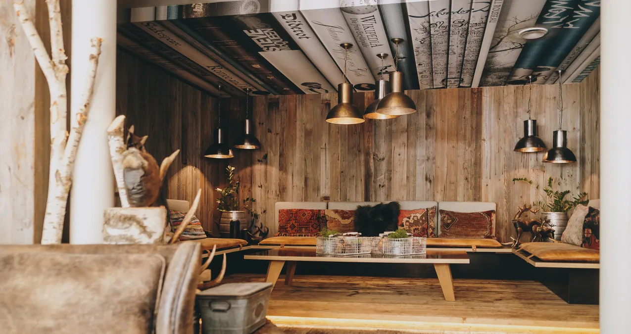 Cozy interior with wooden walls, hanging lamps, and a table.