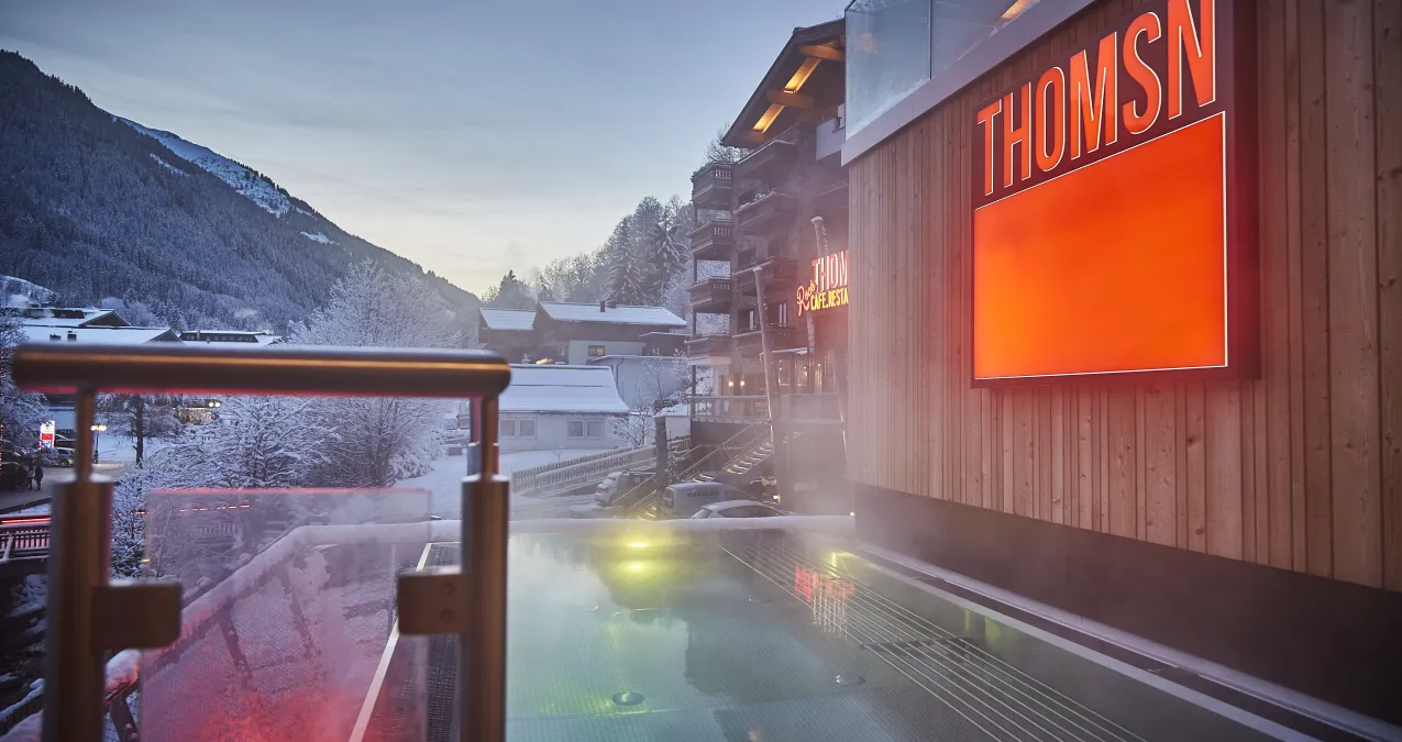 Schneelandschaft mit Wellnesspool und einem Gebäude mit der Aufschrift THOMSN