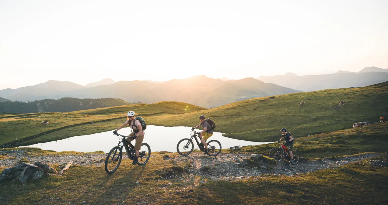 E-Mountainbiker fahren bei Sonnenuntergang in Saalbach.