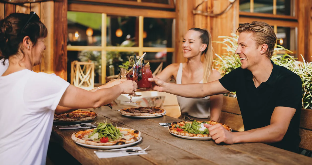 Drei Personen genießen Essen und Getränke im Restaurant.