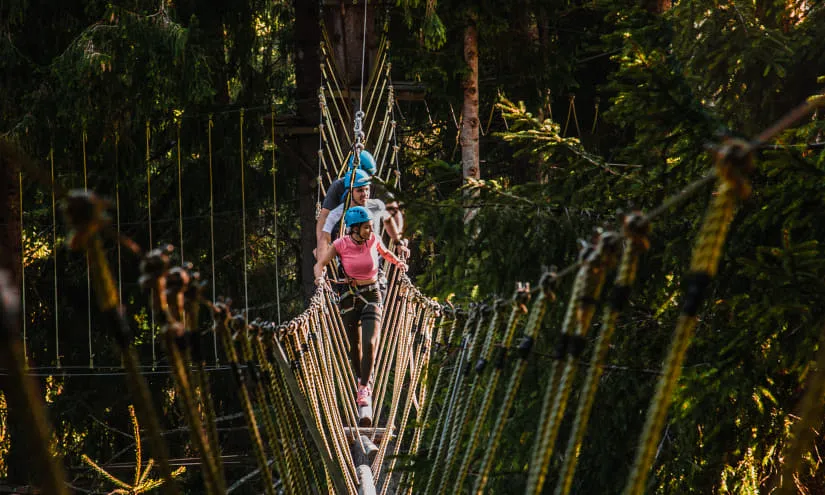 Menschen auf einer Seilbrücke im Hochseilpark.