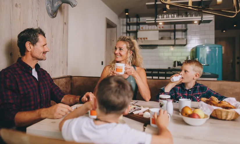 Familie sitzt am Tisch, genießt Snacks und Getränke in einem gemütlichen Raum.