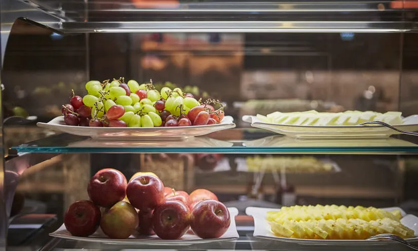 Eine Anzeige von Trauben, Äpfeln und geschnittenem Ananas auf Tabletts.