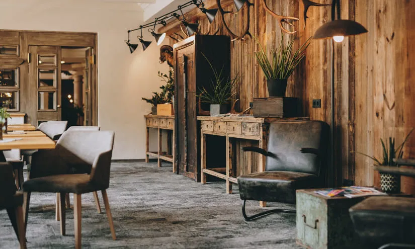 Holzwand mit Pflanzen, antikem Tisch und Stühlen in einem gemütlichen Raum.