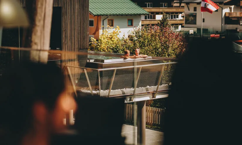 Blick auf einen Pool in Thomsn-Hinterglemm mit Menschen und österreichischer Flagge