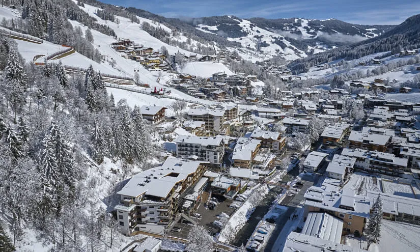 Schneebedeckte Landschaft mit einem Dorf und Bergen im Hintergrund.