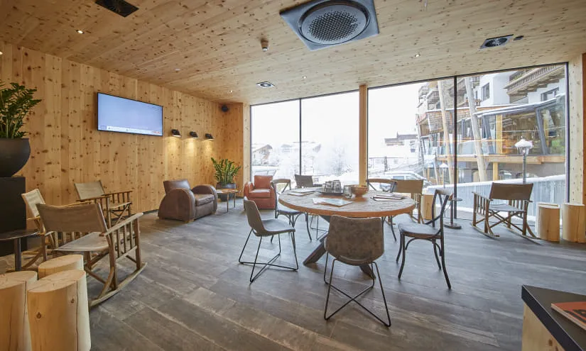 Innenansicht eines Holzcafés mit Sitzgelegenheiten und großen Fenstern