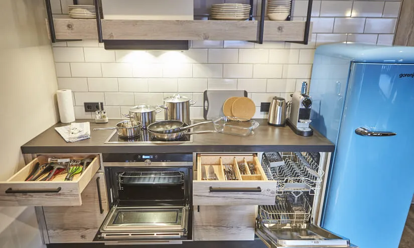Modern kitchen with blue fridge, pots, and open drawers