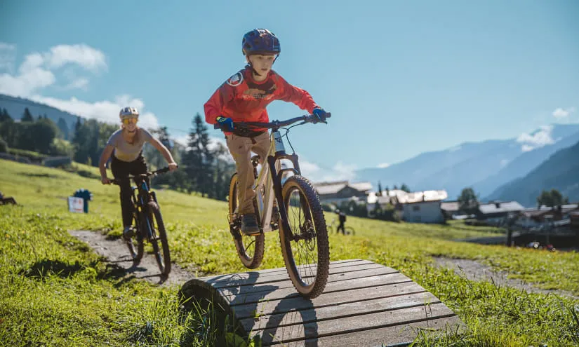 Two kids biking in a park with mountains in the background