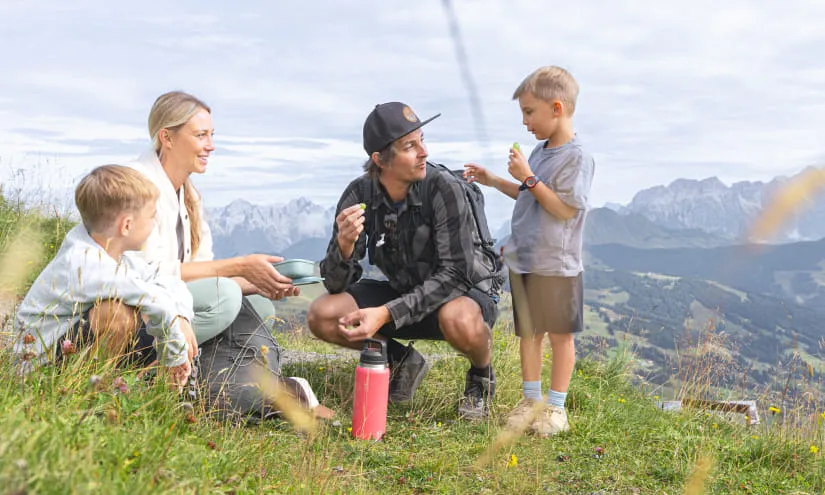 Family hiking, taking a break with snacks in the mountains