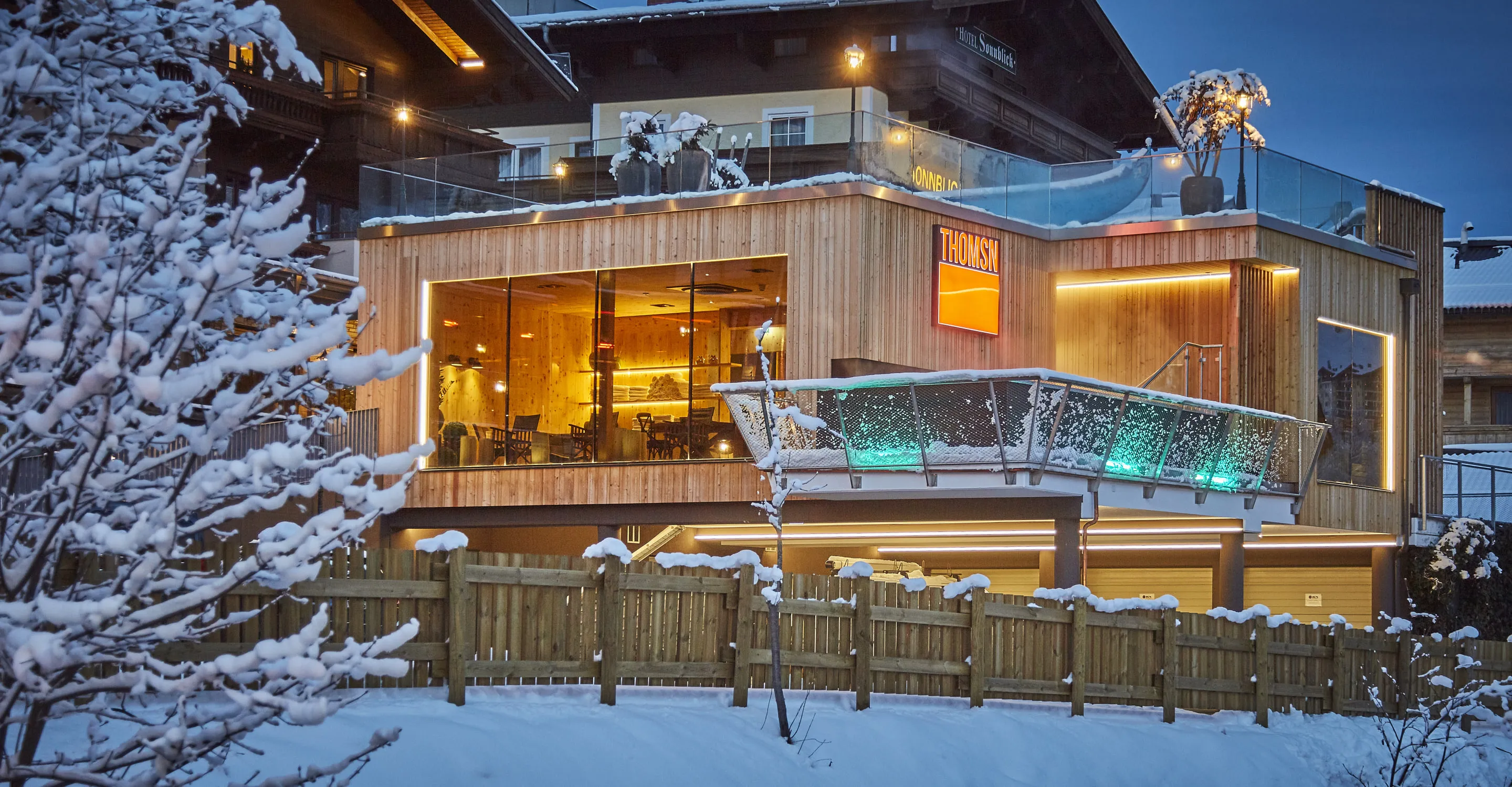 Schnee bedeckte Lodge mit warmen Lichtern und Holzausstattung