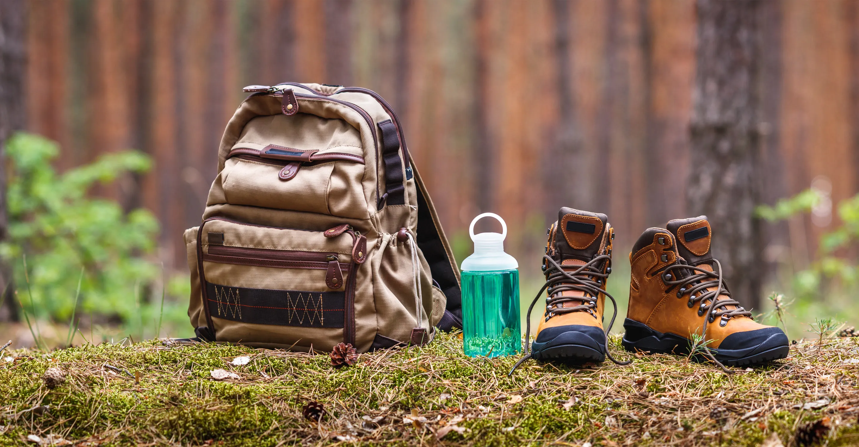Backpack, water bottle, and hiking boots in a forest