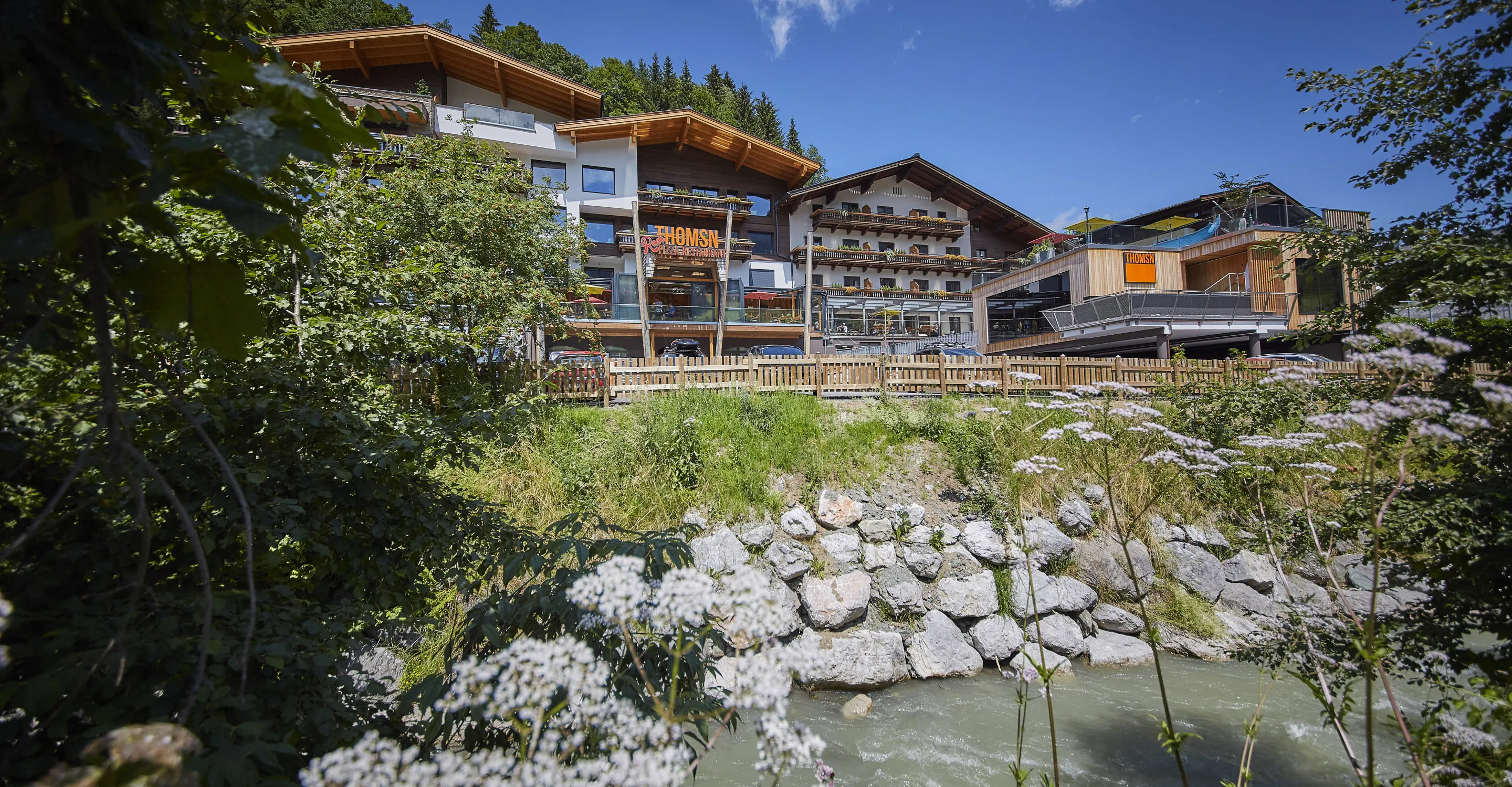 Scenic view of buildings near a river and lush greenery.
