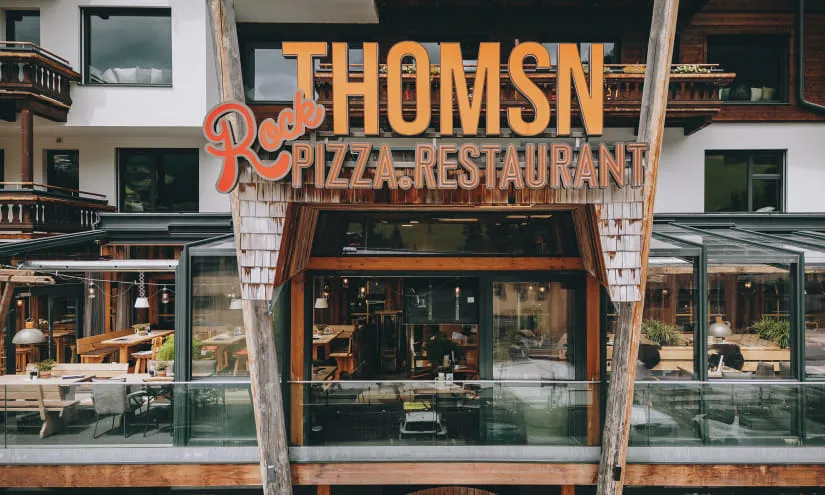 Facade of THOMSEN restaurant with outdoor seating and sign.